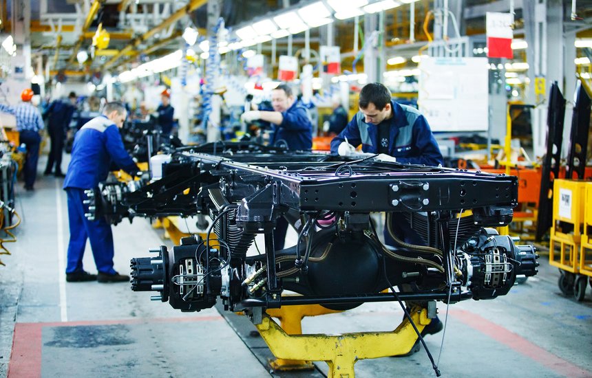 Рабочие собирают машину на заводе. Четырехдневная рабочая неделя